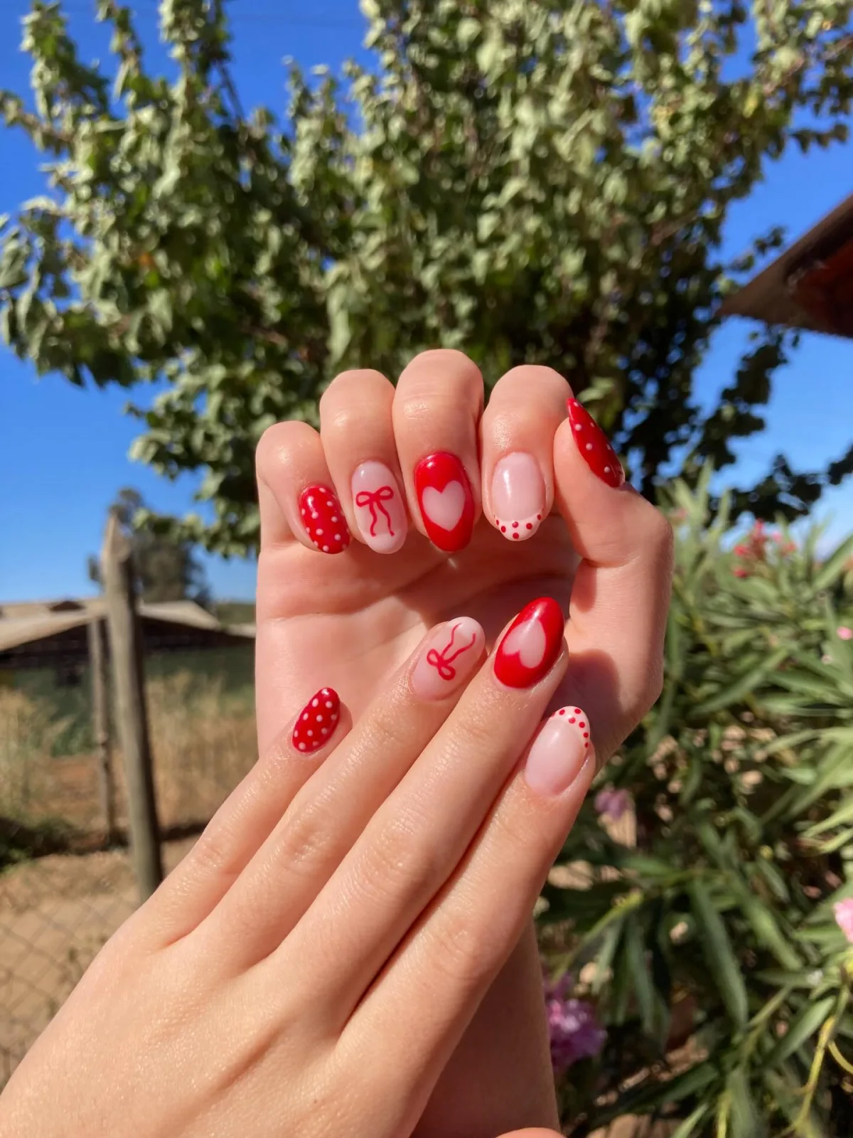 Manicure roja y rosa con corazones, lazos y puntos